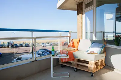 a balcony with a chair and a table on a balcony at Sterflat 63 in Egmond aan Zee