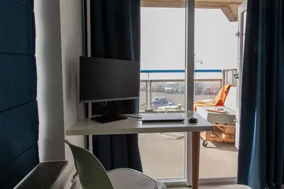 a room with a desk with a television and a window at Sterflat 63 in Egmond aan Zee