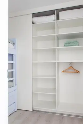 a white walk in closet with white shelves at Sterflat 63 in Egmond aan Zee