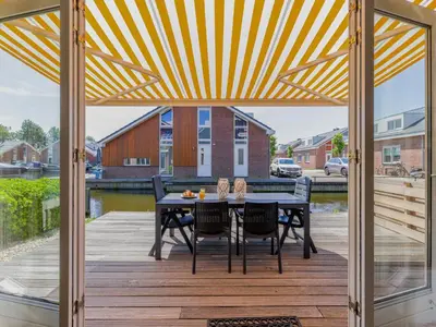 a patio with a black table and chairs on a wooden deck at Assum Great in Uitgeest