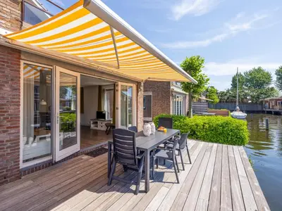 a patio with a table and chairs on a wooden deck at Assum Great in Uitgeest