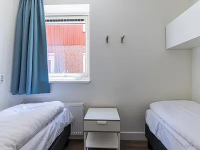 two beds in a small room with a window at Assum Great in Uitgeest