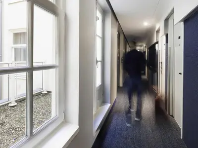 a person walking down a hallway with windows at ibis Styles Amsterdam Central Station in Amsterdam
