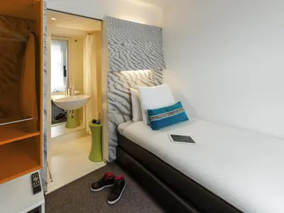 a small bedroom with a bed and a sink and a mirror at ibis Styles Amsterdam Central Station in Amsterdam