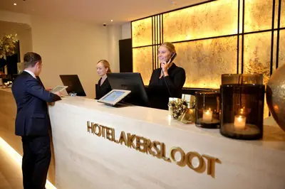 a man and two women standing at a hotel reception counter at Van der Valk Hotel Akersloot / A9 ALKMAAR in Akersloot