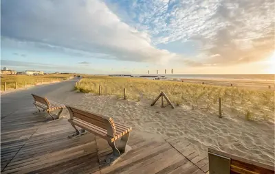 two benches sitting on a boardwalk next to the beach at Gorgeous Apartment In Katwijk Aan Zee in Katwijk aan Zee