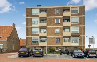 a tall brick building with cars parked in a parking lot at Gorgeous Apartment In Katwijk Aan Zee in Katwijk aan Zee
