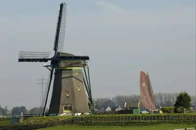 a windmill in a field next to a building at Glamping de Hof van Eeden in Warmond