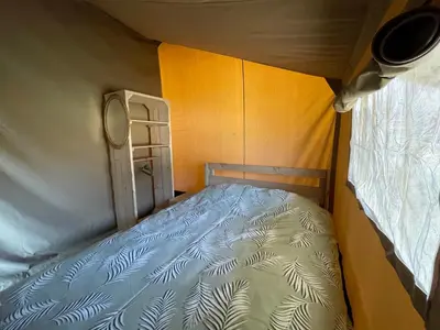 a small bedroom with a bed and a window at Glamping de Hof van Eeden in Warmond
