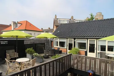 a balcony with tables and chairs and umbrellas at Hofje van Maas in Zandvoort