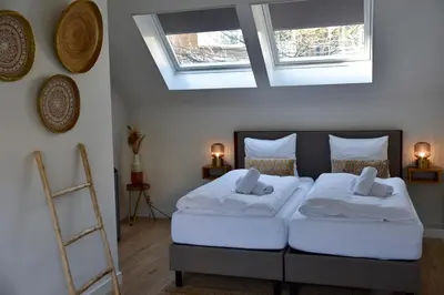 a bedroom with two beds and two windows at Hofje van Maas in Zandvoort