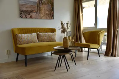 a living room with a yellow couch and a table at Hofje van Maas in Zandvoort
