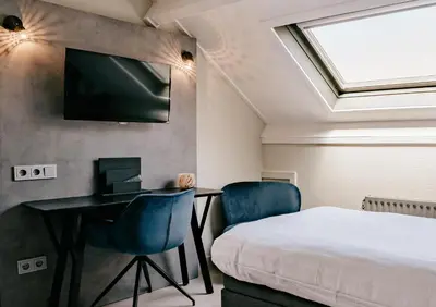 a bedroom with a bed and a desk and a tv at Hotel Heemskerk in Heemskerk