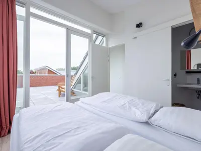 a bedroom with a white bed and a large window at Holiday Home De Meerparel by Interhome in Uitgeest
