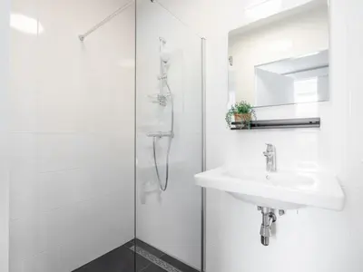a white bathroom with a sink and a shower at Holiday Home De Meerparel by Interhome in Uitgeest