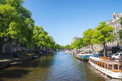 a river with boats in a city with buildings at Hotel Alexander in Amsterdam