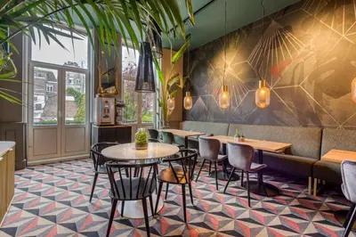a restaurant with tables and chairs and a couch at Hotel Alexander in Amsterdam