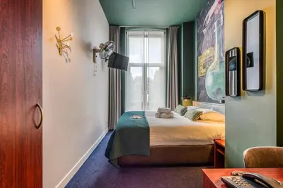 a bedroom with a bed with a teddy bear on it at Hotel Alexander in Amsterdam
