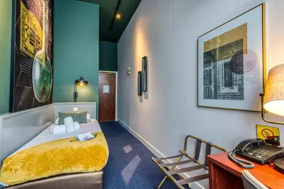 a room with a bed and a desk with a telephone at Hotel Alexander in Amsterdam