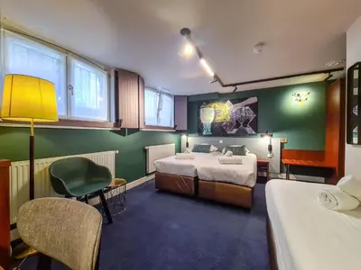 a room with two beds and a table and chairs at Hotel Alexander in Amsterdam