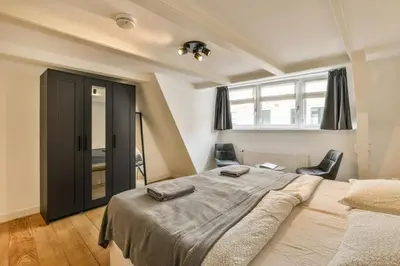 a bedroom with a large bed and two chairs at Amsterdam Alley Apartment in Amsterdam