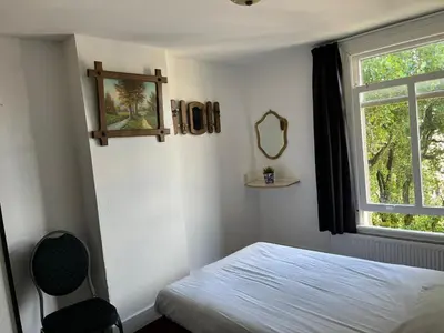 a bedroom with a bed and a window and a mirror at Hotel Galerij in Amsterdam