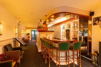 a kitchen with a bar with green bar stools at Owl Hotel in Amsterdam