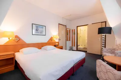 a hotel room with a large bed and a chair at Owl Hotel in Amsterdam