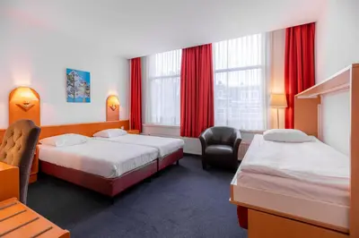 a hotel room with two beds and a chair at Owl Hotel in Amsterdam