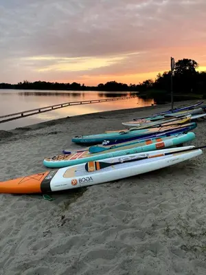 a group of kayaks lined up on a beach at Hotel Café Restaurant Heineke in Loosdrecht