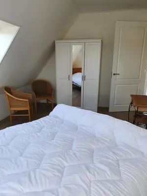a bedroom with a large white bed and two chairs at Mathildahoeve in Warder
