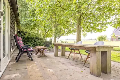a wooden table and chairs on a patio at Het Kamphuis, landelijk slapen in Heerhugowaard