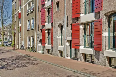 a row of buildings with red windows on a street at City-centre, Canal-house, luxurious , stylish bedroom, ensuite bathroom in Amsterdam