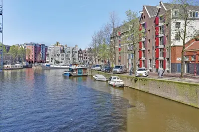 a river with boats in a city with buildings at City-centre, Canal-house, luxurious , stylish bedroom, ensuite bathroom in Amsterdam