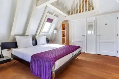 a bedroom with a large bed with a purple blanket at City-centre, Canal-house, luxurious , stylish bedroom, ensuite bathroom in Amsterdam