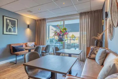 a living room with tables and chairs and a couch at Hotel De Koningshof in Noordwijk aan Zee