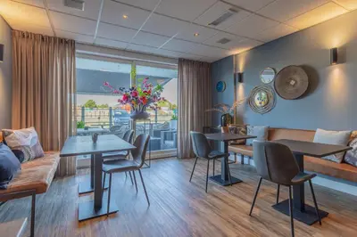 a living room with tables and chairs and a couch at Hotel De Koningshof in Noordwijk aan Zee