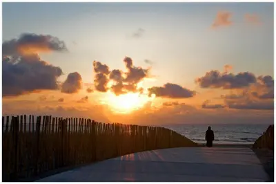 a person standing on a pier looking at the sunset at Hotel De Koningshof in Noordwijk aan Zee