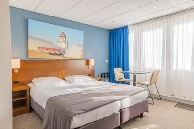 a hotel room with a large bed and a table at Hotel De Koningshof in Noordwijk aan Zee
