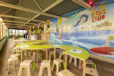 a classroom with tables and stools and a mural at Beachhotel Zandvoort by Center Parcs in Zandvoort