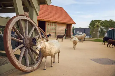 a group of sheep standing next to a wooden wheel at Beachhotel Zandvoort by Center Parcs in Zandvoort