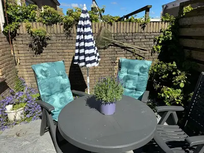 a table and two chairs with a potted plant on a patio at Strandduin - Vakantiewoning aan de Kust - 52 in Egmond aan Zee
