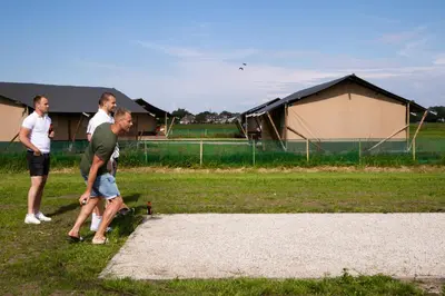 three men standing in a field playing with a frisbee at Camping de Speld in Nieuwkoop