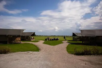 a group of people sitting in the grass near buildings at Camping de Speld in Nieuwkoop