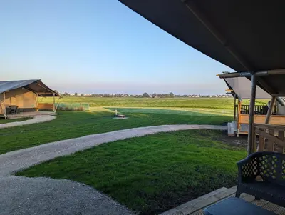 a patio with a bench and a field of grass at Camping de Speld in Nieuwkoop