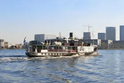a boat on the water with a city in the background at Kapitein Anna in Amsterdam