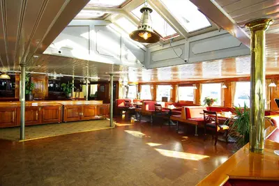 a restaurant with red chairs and tables and windows at Kapitein Anna in Amsterdam