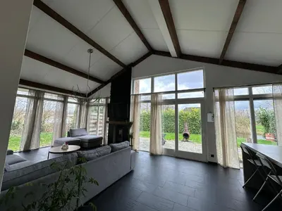 a living room with a couch and some windows at Groot vakantiehuis nabij Amsterdam inclusief jacuzzi in Zeewolde