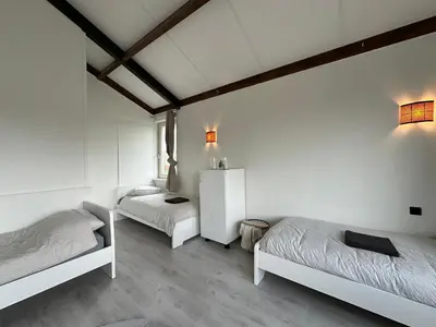 two beds in a room with white walls and wooden ceilings at Groot vakantiehuis nabij Amsterdam inclusief jacuzzi in Zeewolde