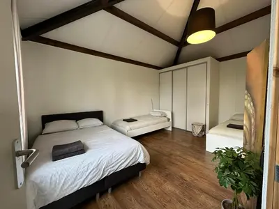 a bedroom with two beds and a wooden floor at Groot vakantiehuis nabij Amsterdam inclusief jacuzzi in Zeewolde